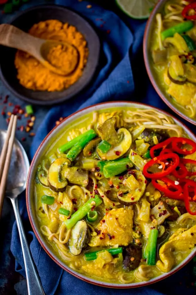 overhead close up photo of a bowl of Chicken Noodle Soup with Turmeric on a dark background with turmeric in the background