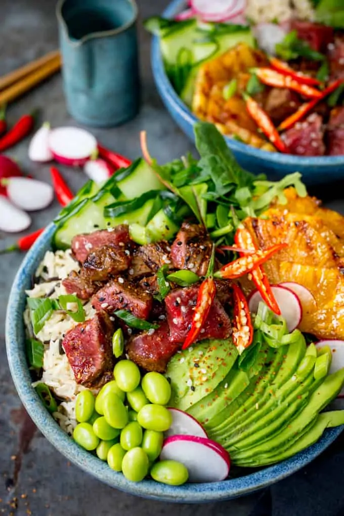 Steak poke bowl with avocado and pineapple in a blue bowl