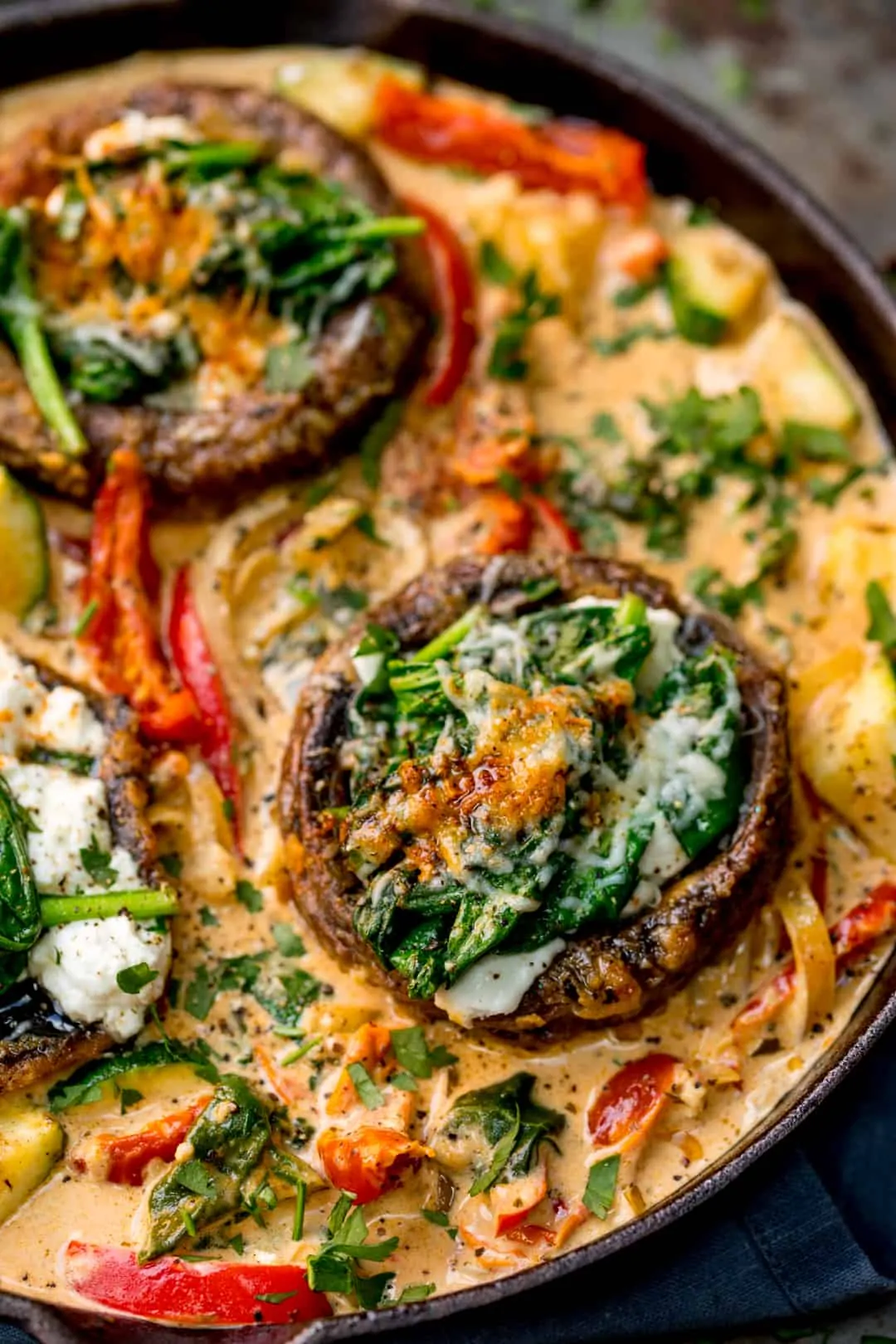 Overhead close up of Tuscan Style Stuffed Mushrooms in Creamy Sun Dried Tomato Sauce in a skillet