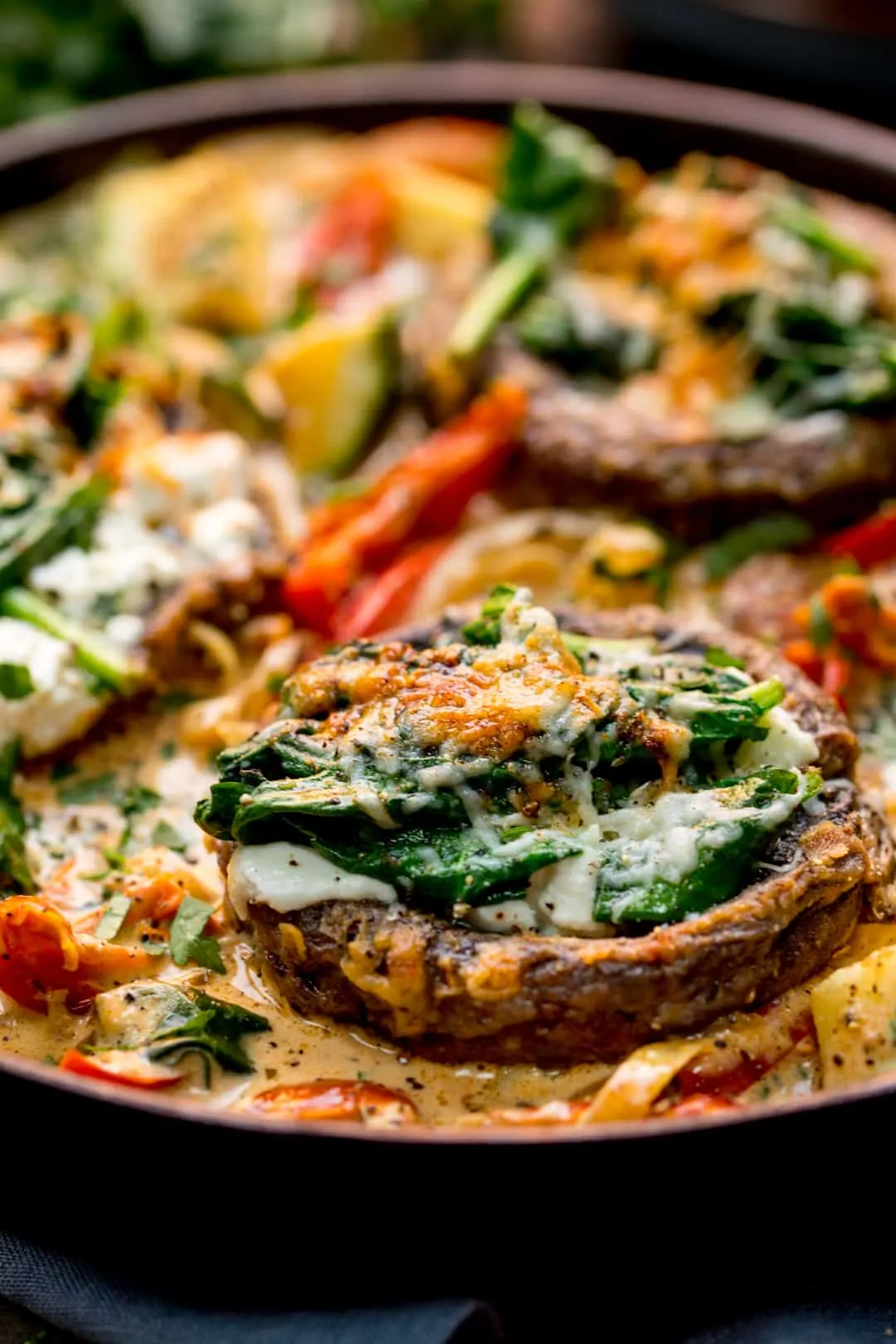 Extreme close up of Tuscan Style Stuffed Mushrooms in Creamy Sun Dried Tomato Sauce in a skillet