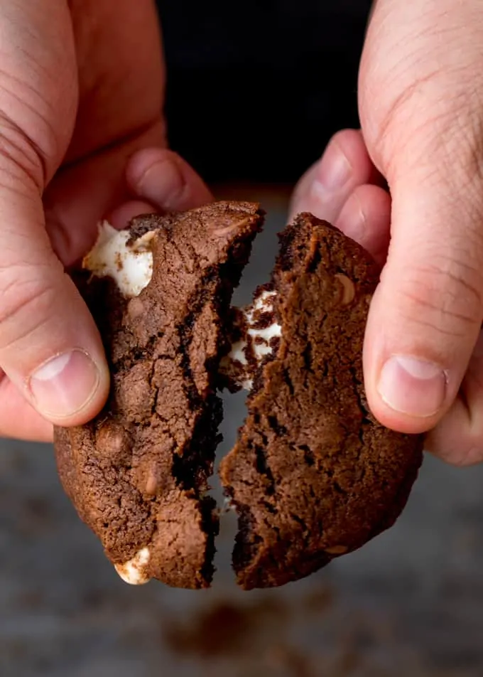 Close up of hands breaking a double chocolate cookie in half