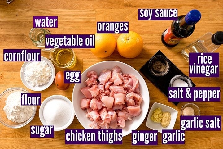 Ingredients for making crispy orange chicken on a wooden table