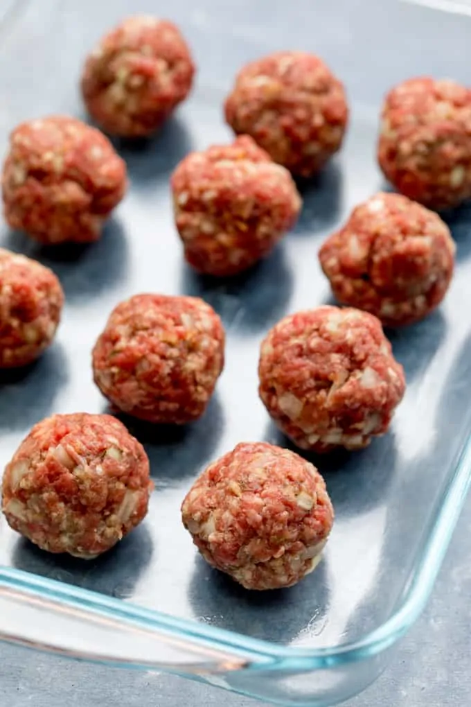 Meatballs lined up in a dish, ready for the oven.