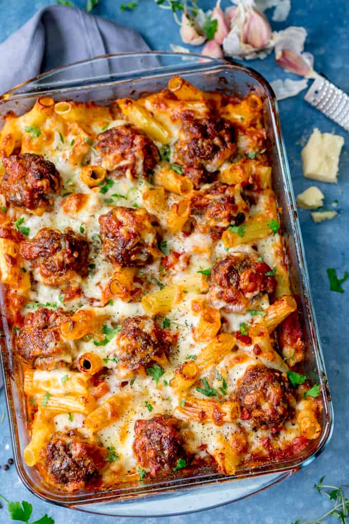 Overhead image of a dish of meatball and pasta bake on a blue background