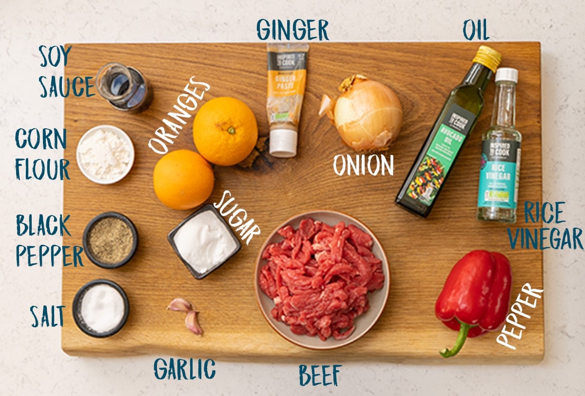 Ingredients for crispy orange beef on a wooden board.