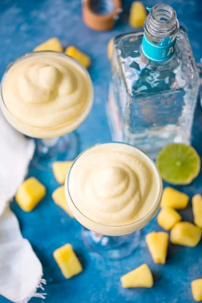 Overhead image of two glasses of dole whip margarita on blue background.