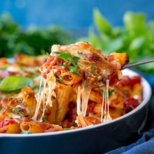 side shot sausage pasta bake. Spoonful being scooped out with cheese stretching.