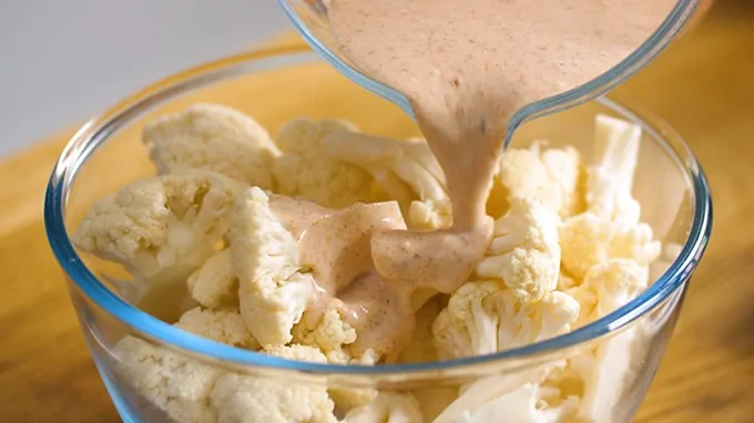 Sauce being poured onto cauliflower florets