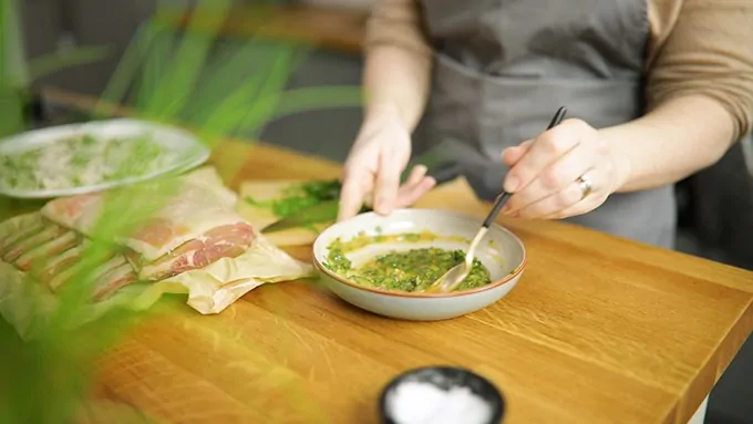 Honey mustard herb sauce being stirred in a grey bowl on a wooden surface