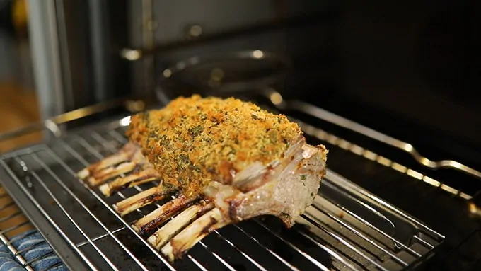 Herb coated rack of lamb coming out of the oven.