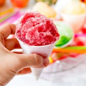 Square image of hand holding cherry flavoured snow cone