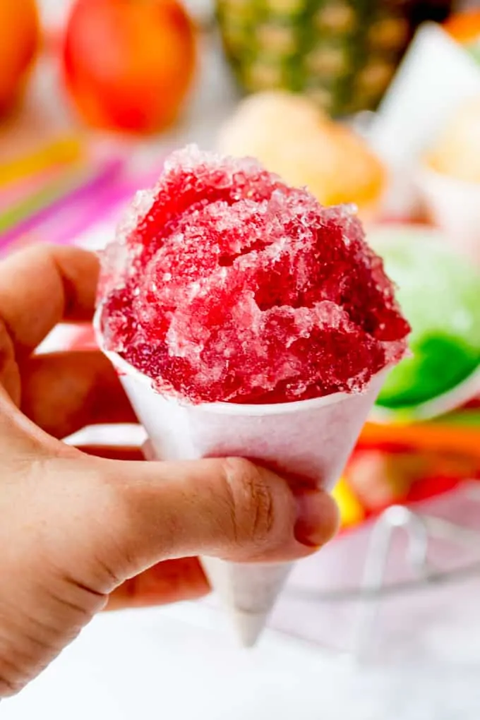 Close up of hand holding cherry flavoured snow cone
