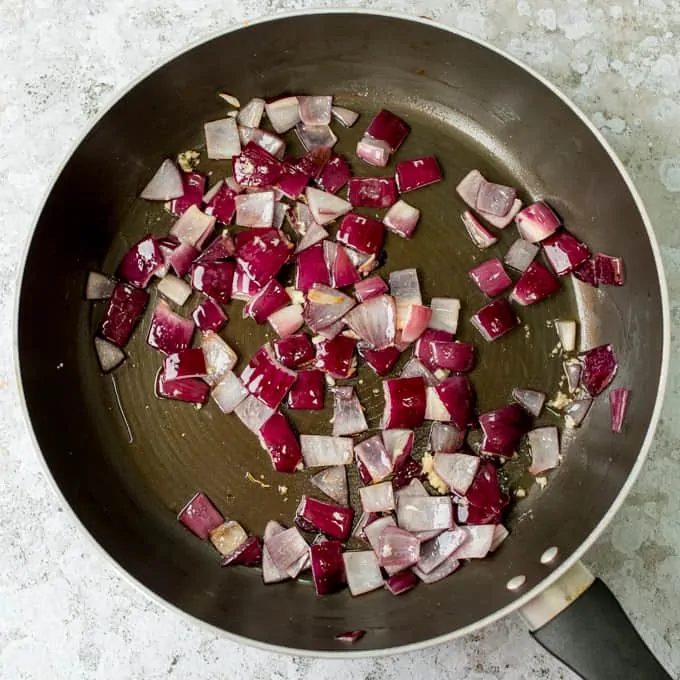 Red onion pieces cooking in pan