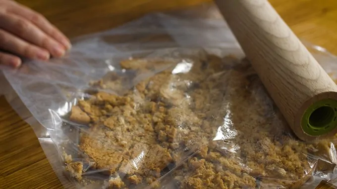 Biscuits in a bag being crushed by a rolling pin