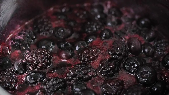 Blueberries and blackberries simmering in pan