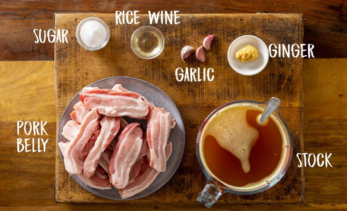 Ingredients for slow cooked pork belly on a wooden table.