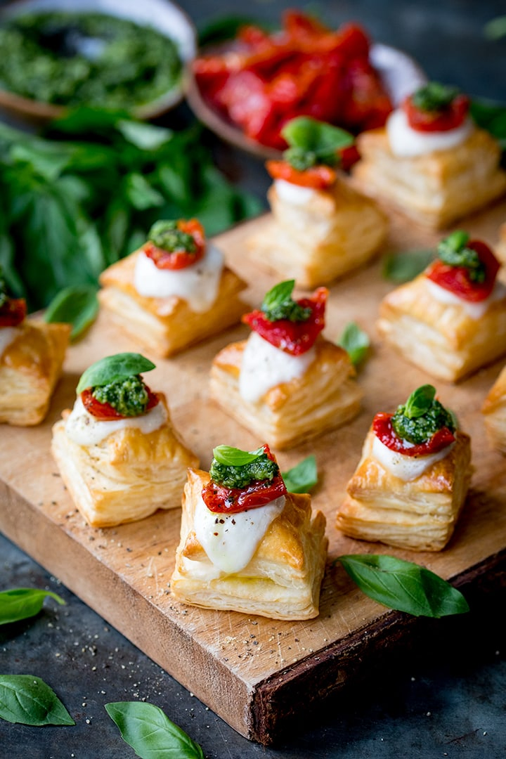 Puff pastry caprese bites - with mozzarella, pesto and sundried tomato - on a serving board