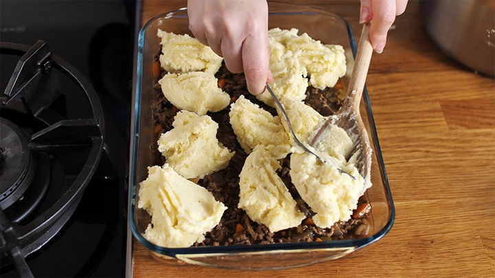 Placing blobs of mashed potato on top of cottage pie