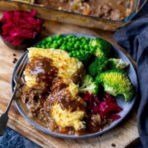 Cottage pie on a plate with broccoli, peas and red cabbage