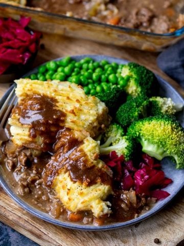 Cottage pie on a plate with broccoli, peas and red cabbage