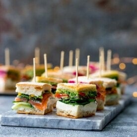 Pressed mini sandwich bites with different fillings on a marble platter