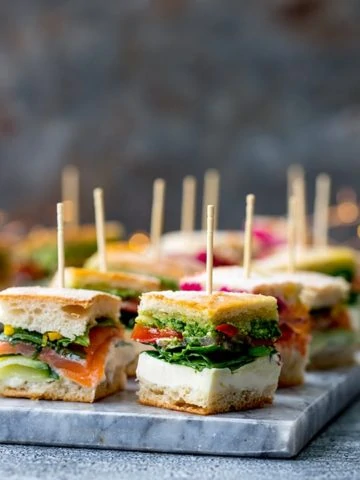 Pressed mini sandwich bites with different fillings on a marble platter