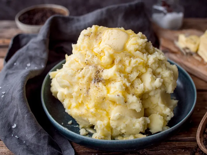 Wide image of mashed potatoes in a blue bowl.