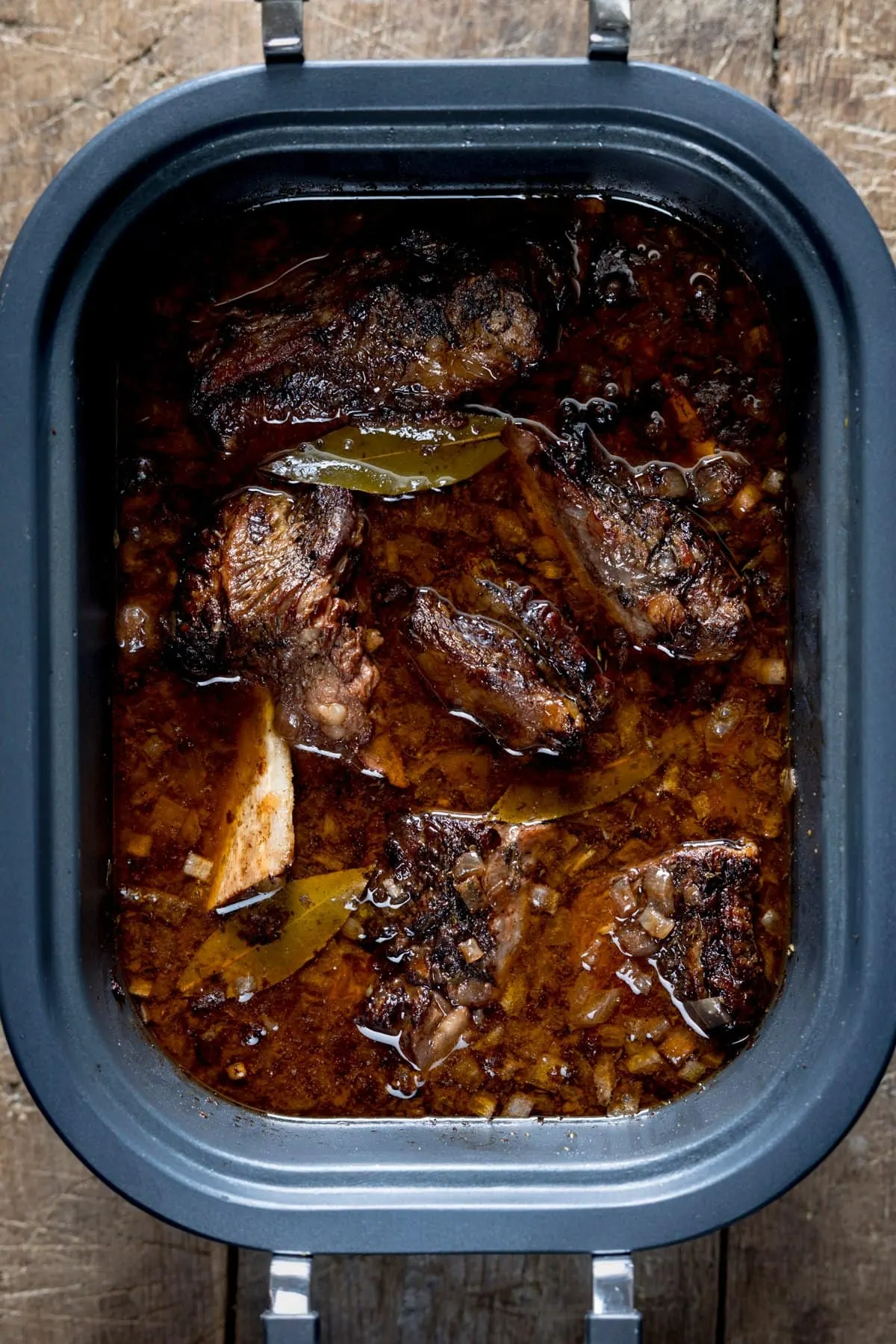 Overhead image of short ribs and gravy being cooked in a slow cooker