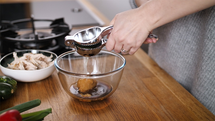 Limes being squeezed into a bowl for thai dressing