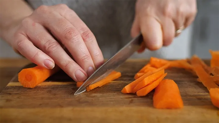 Carrots being sliced on a chopping board