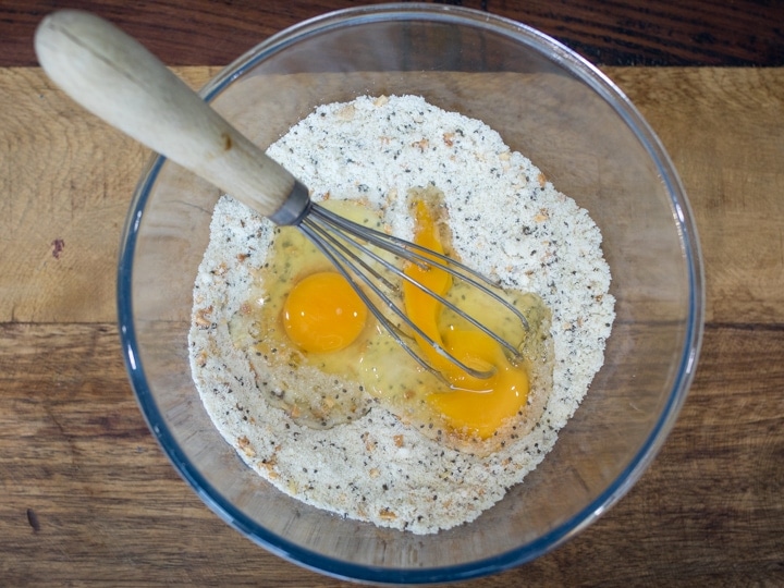 Dry ingredients for chia hazelnut pancakes in a bowl with two eggs