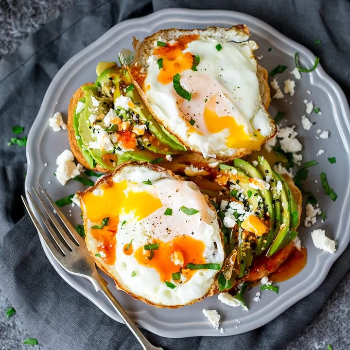 Square image of avocado and eggs on toast with feta and sweet chilli sauce