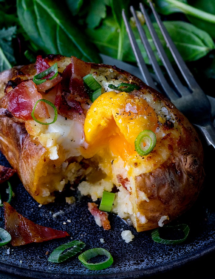 Close up of baked potato stuffed with baked egg and bacon