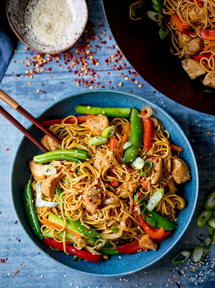 Overhead image of chicken lo mein in blue bowl with chopsticks
