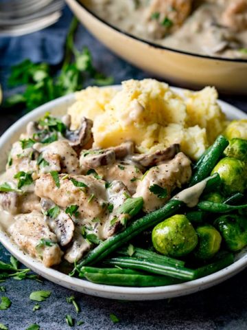 Bowl of creamy chicken and mushroom casserole with mashed potatoes, sprouts and green beans.