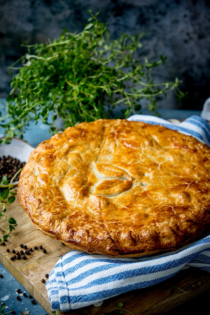 chicken and mushroom pie on a wooden table with a blue and white striped tea towel