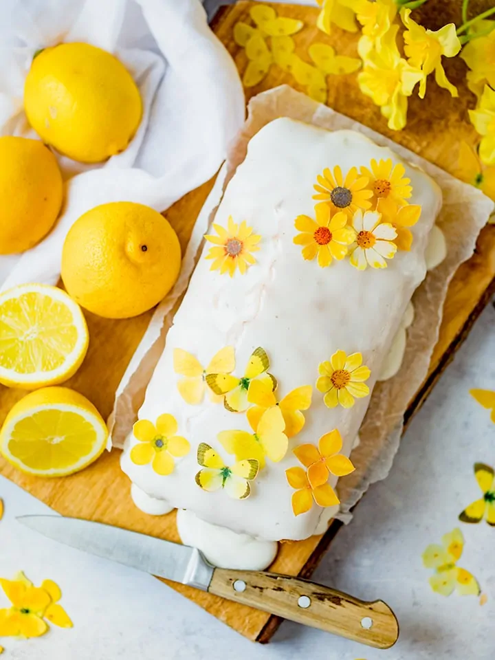 Overhead photo of vegan lemon drizzle cake with sugar flowers on top