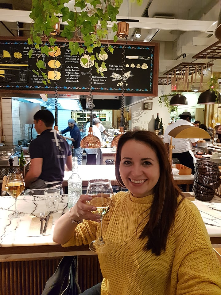 Nicky holding a glass of wine in Eataly in New York