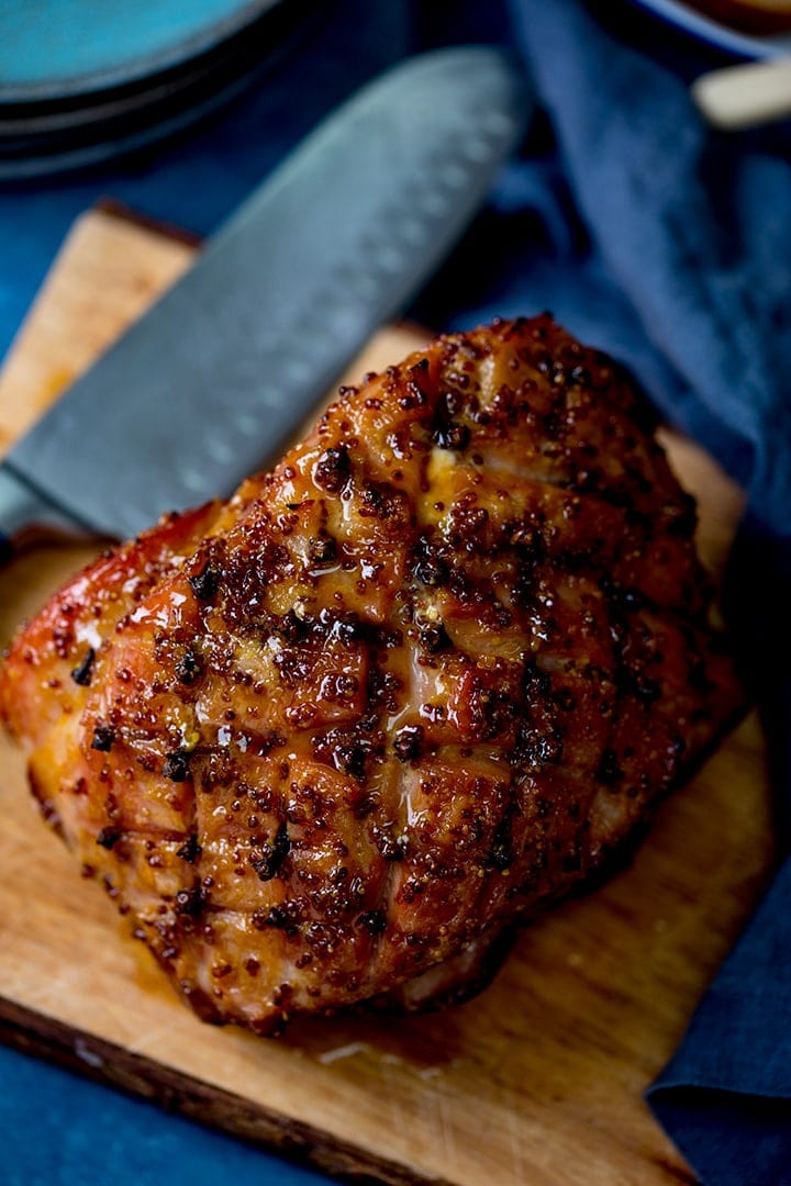 Baked ham with honey mustard glaze and cloves on a chopping board