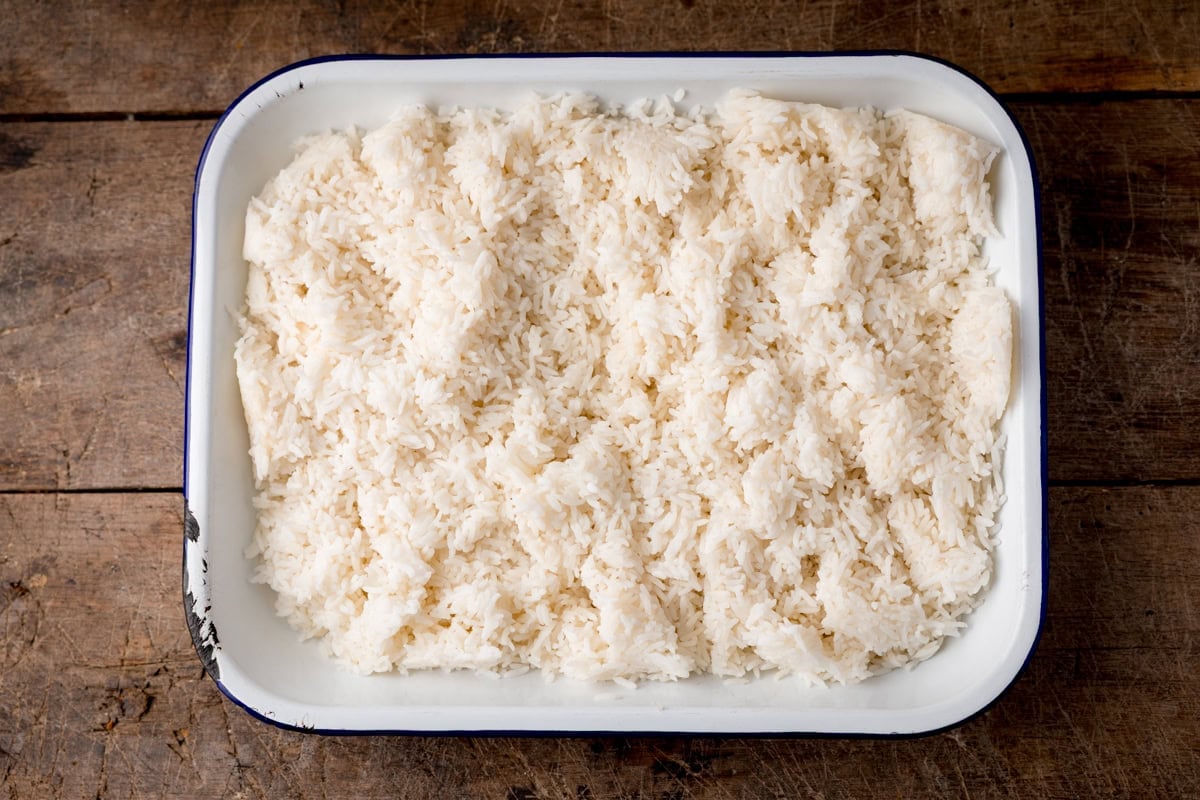 A rectangular enamel dish filled with cooked white rice.