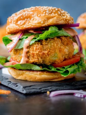 Cheesy Veggie Burger with lettuce on sesame seed bun on blue background