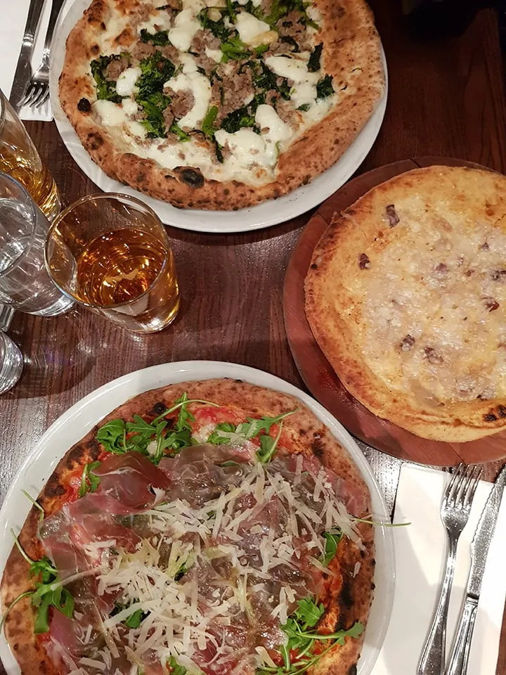 Three pizzas on a table at Don Antonio's New York