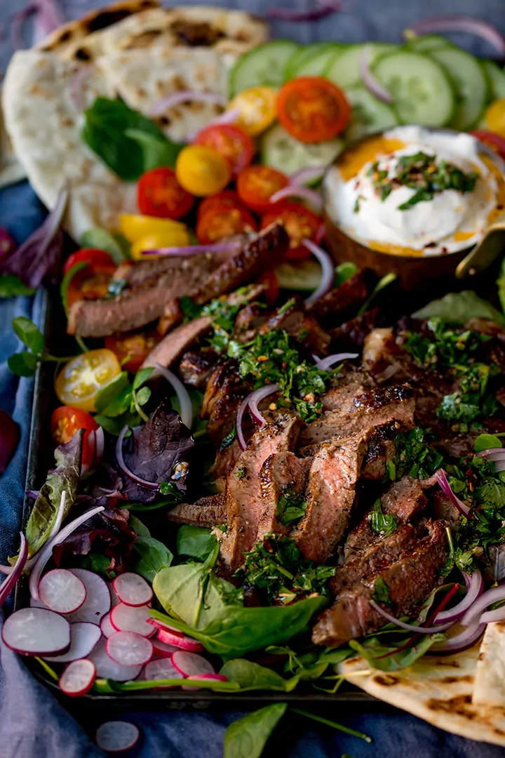 Close up image of chimichurri steak salad platter on a dark background