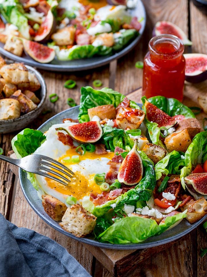 Breakfast salad bowl with bacon, fried egg, croutons, figs and lettuce