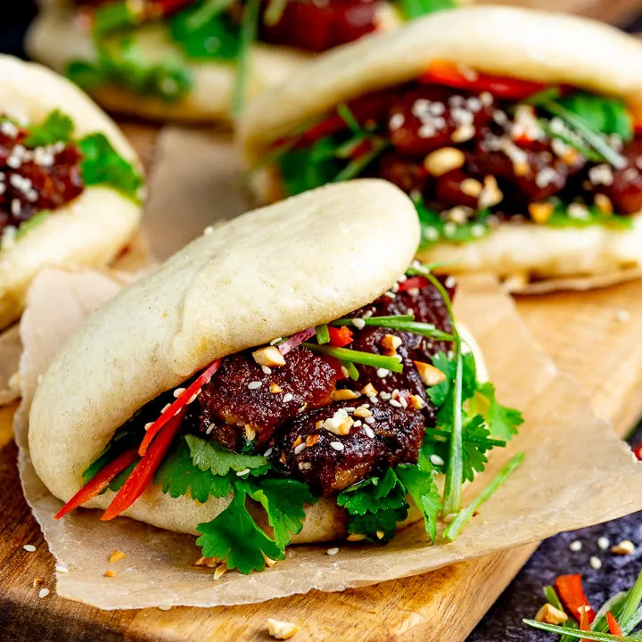 Gua Bao pork belly buns on a wooden board with another one in the background