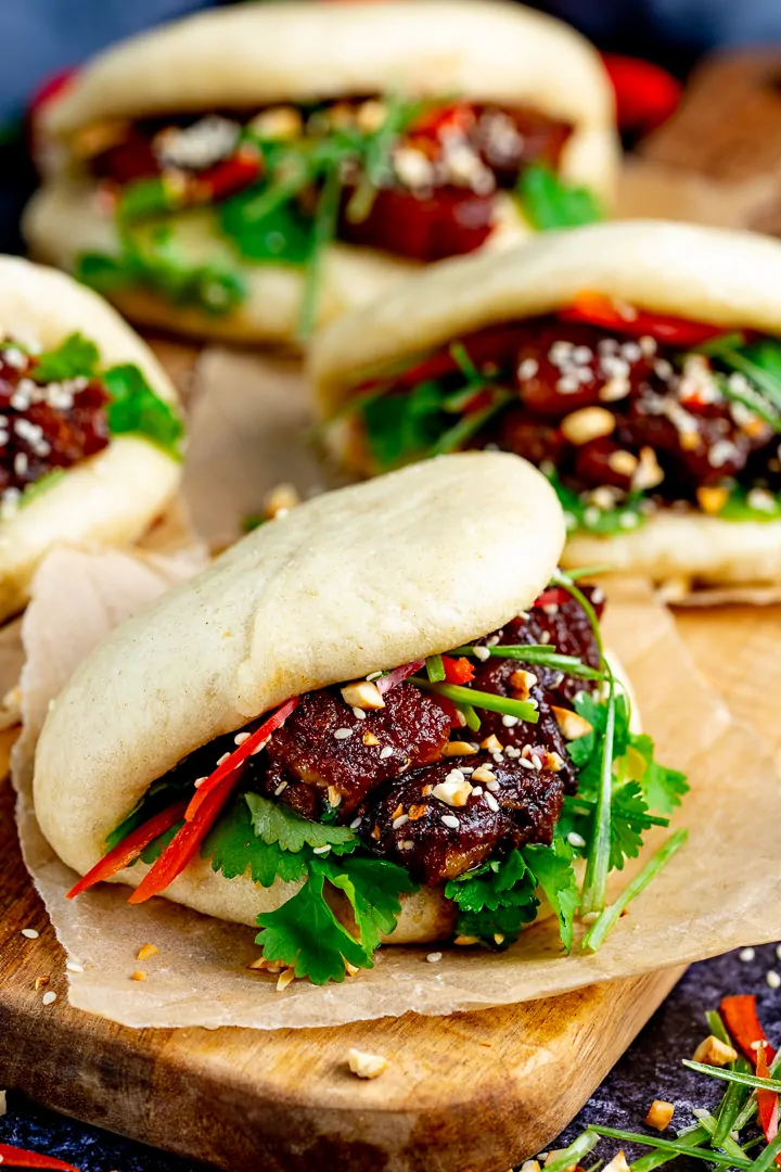 Tall image of Gua Bao pork belly buns on a wooden board