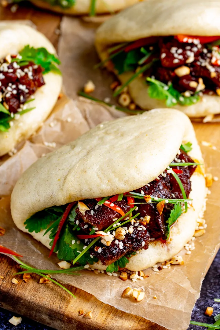 Gua Bao pork belly buns with coriander and spring onions on a wooden board
