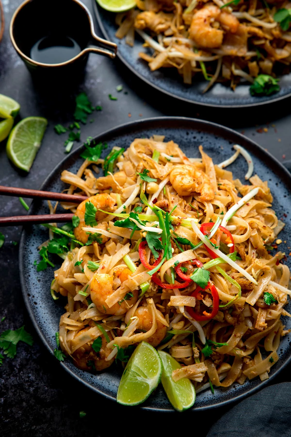 Overhead image of Prawn Pad Thai on a black plate on a black bakcground