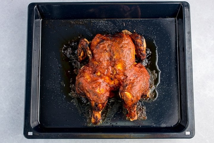 Roasted peri peri chicken on a dark tray
