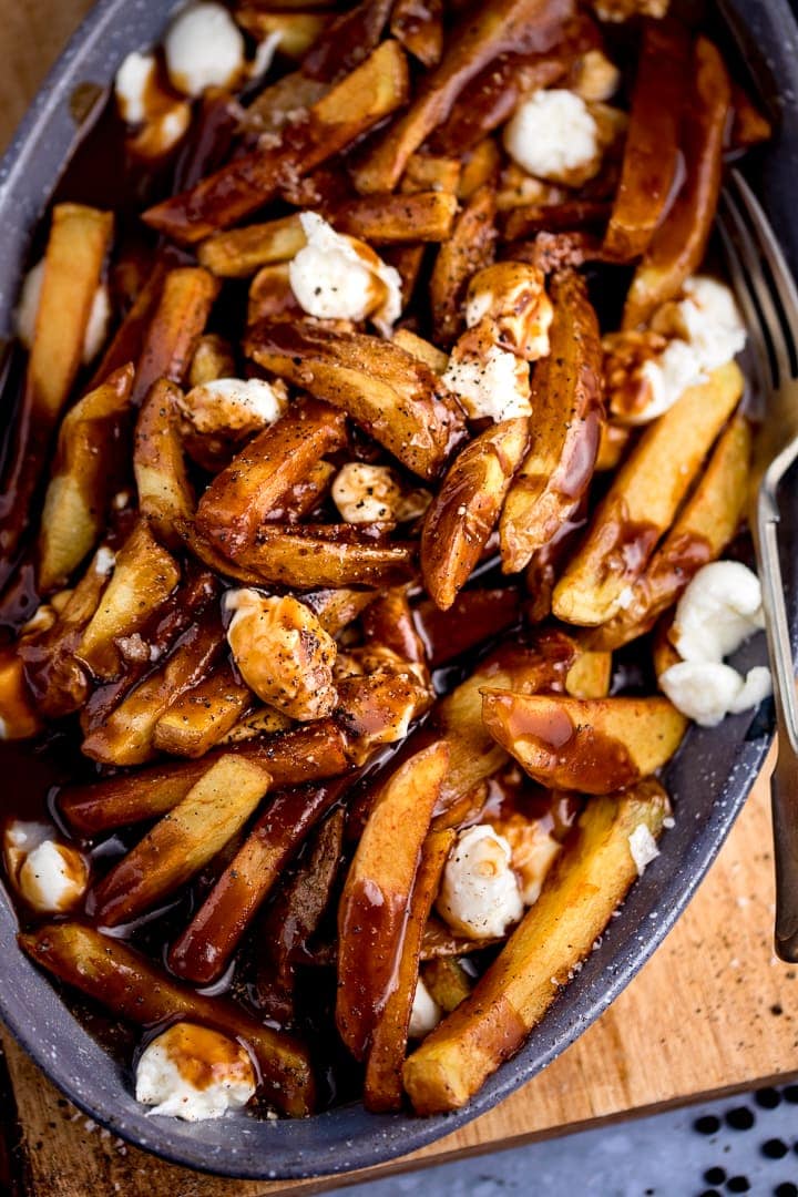 overhead image of Poutine in a grey dish on a wooden board